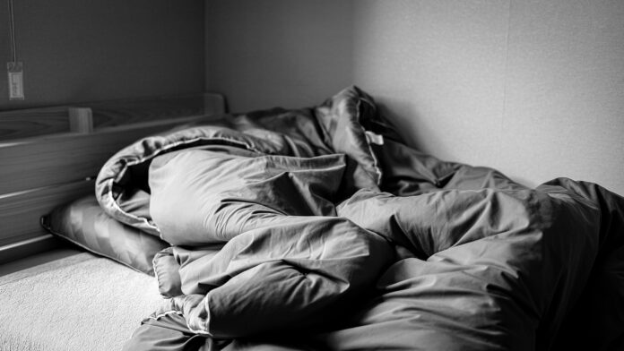 a black and white photo of an unmade bed