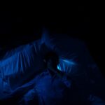 “잠이 보약”…현대인 위한 수면 혁신 트렌드와 실전 꿀팁 A person laying in a bed in a dark room