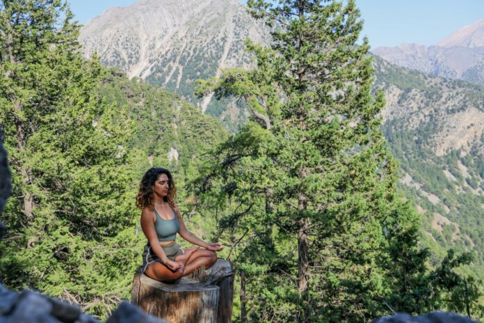 Photo by Mor Shani woman in black tank top sitting on brown wooden log during daytime