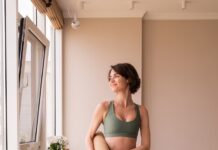 바쁜 일상 속 ‘필라테스’, 건강과 마음을 다잡는 새로운 습관 a woman in a green sports bra top and leggings holding a yoga mat