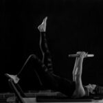 집에서 만나는 필라테스, 건강한 일상의 새로운 기본으로 자리잡다 woman in black pants and black boots lying on black wooden bench